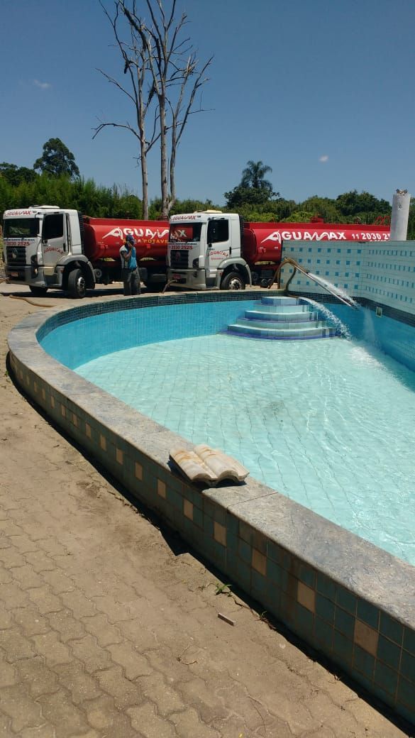 Dois caminhões Aguamax enchendo piscina em chácara