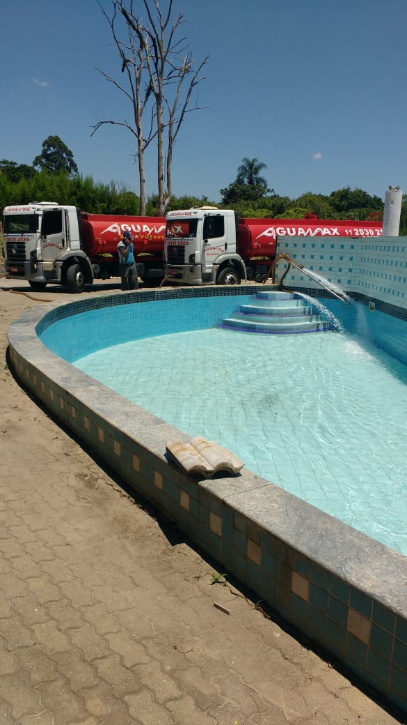 Dois caminhões Aguamax enchendo piscina em chácara